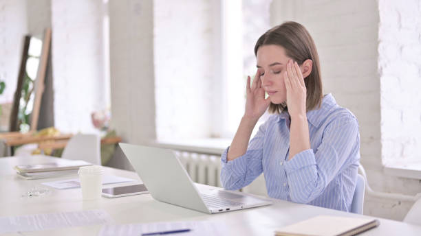 istock Tired Young Woman having Headache in Modern Office 1219498611
