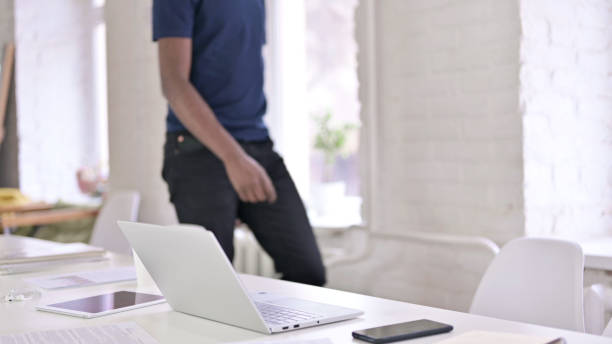 istock Young African Man Coming in and Sitting in Office 1219498652