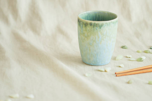 tre mochi colorati luminosi su un piatto verde e una tazza di caffè su un tessuto beige. - pastel colored foto e immagini stock