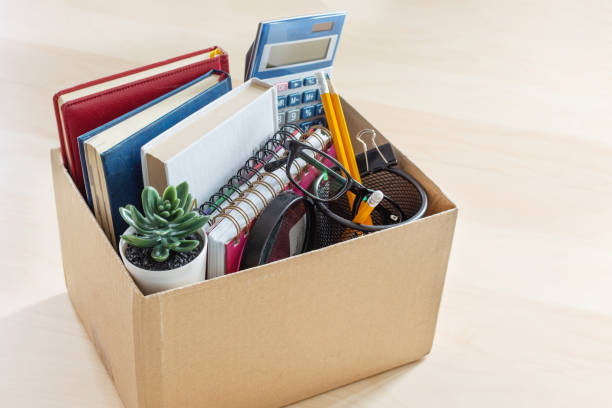 Cardboard box with office suplies on the desk. Dismissal of employment and resignation concept. Cardboard box with office suplies on the desk. Dismissal of employment and resignation concept. Bankruptcy and economy crisis. belongings stock pictures, royalty-free photos & images