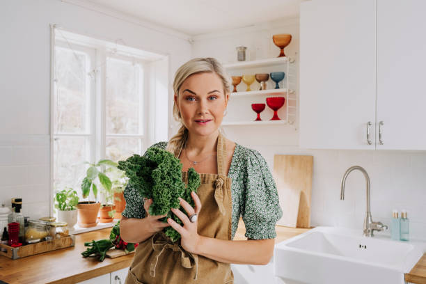 istock Woman at home in kitchen with vegetables kale 1219509039