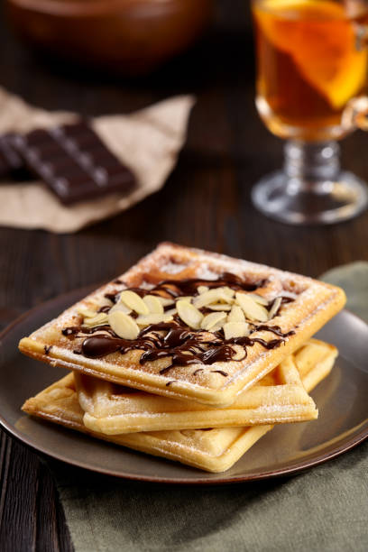 istock Beautiful breakfast. Belgian Viennese waffles decorated  with chocolate and strawberries, tea on a dark background. 1219509521