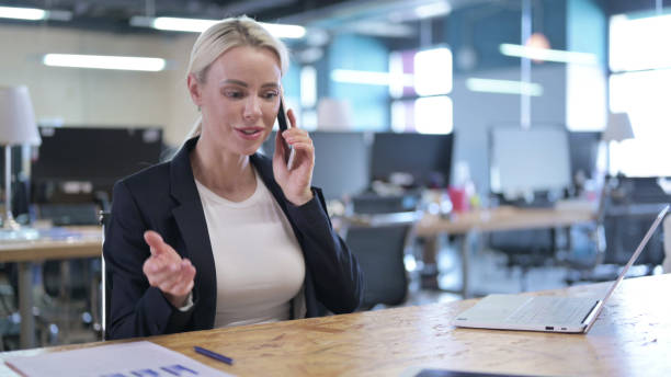 istock Cheerful Businesswoman Talking on Smartphone at Work 1219513342