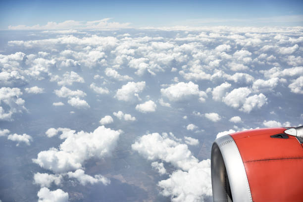 Beautiful view through the window of the plane, view of the engine, sky and clouds. Airplane flying over the sea of clouds. Travel and artistic concept