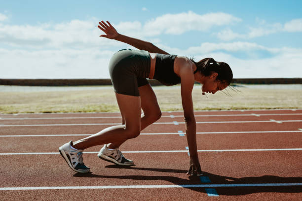 istock Woman runner at the start line taking position on a running track 1219515404