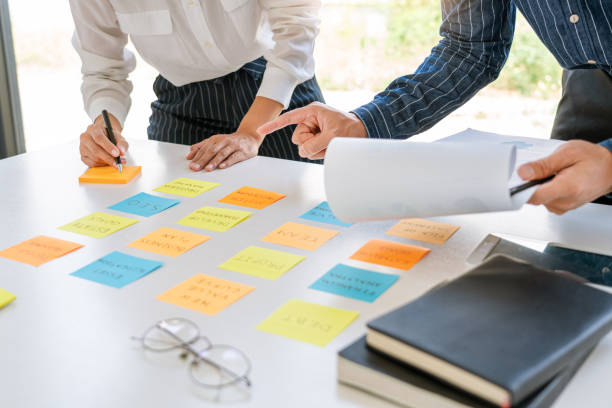 istock young business workers posting with sticky notes stickers reminders  creative brainstorming at board the colleague in a modern co-working space 1219516177