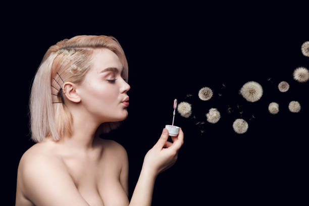 Young woman blows dandelion