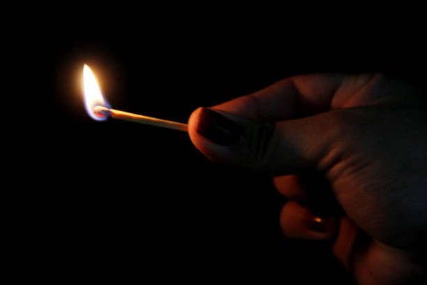 Burning match stick in darkness. Fire in the dark.