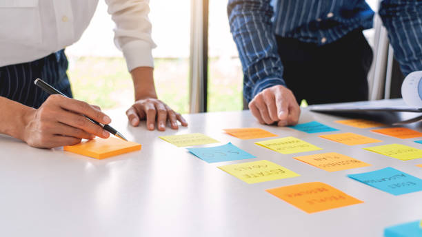 istock young business workers posting with sticky notes stickers reminders  creative brainstorming at board the colleague in a modern co-working space 1219516838