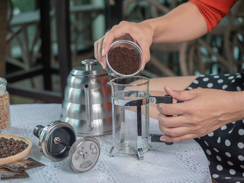 prepare to make coffee by french press technic, pouring ground coffee into the jar.