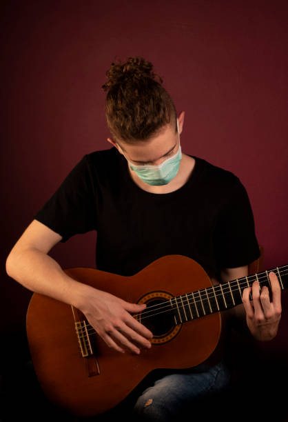 istock Playing guitar in protection mask 1219520331