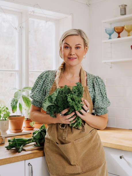 Woman at home in kitchen with vegetables kale