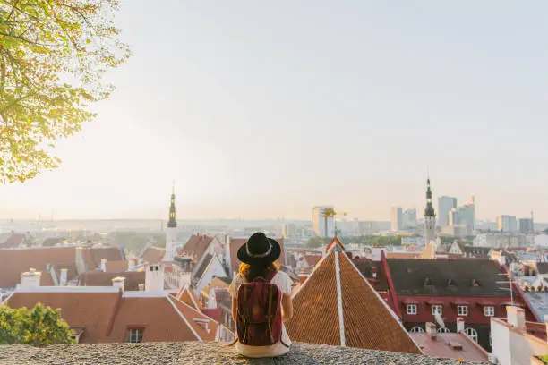 Young Caucasian woman sitting and looking at Tallinn in the morning