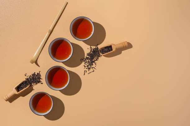 thé puer noir dans des bols en céramique, feuilles sèches de thé pu-erh dans une cuillère en bambou en bois sur un fond beige, minimalisme de cérémonie de thé. - chinese tea photos et images de collection