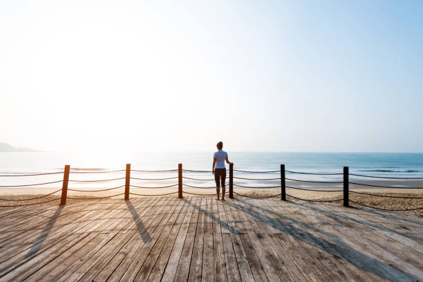 Woman standing on boardwalk at the beach.