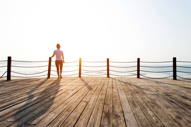 istock Woman standing on boardwalk at the beach 1219526573