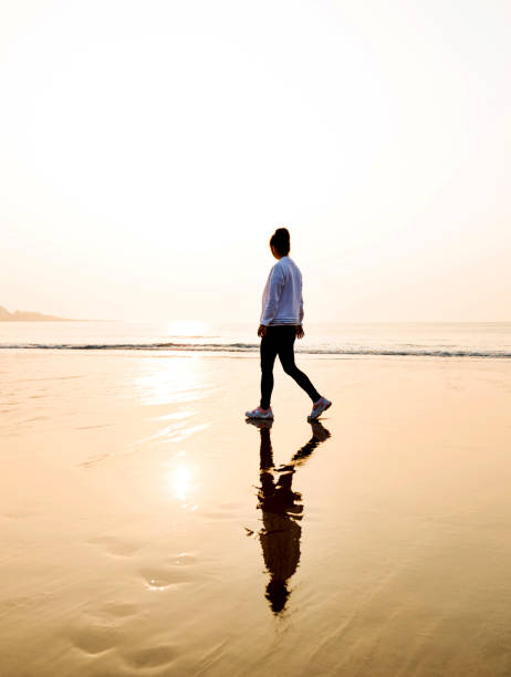istock Woman walking on the beach at sunset 1219527241