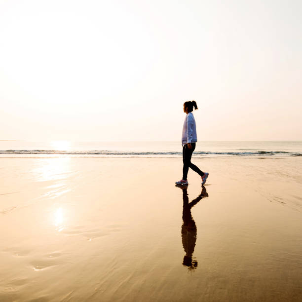 istock Woman walking on the beach at sunset 1219527243