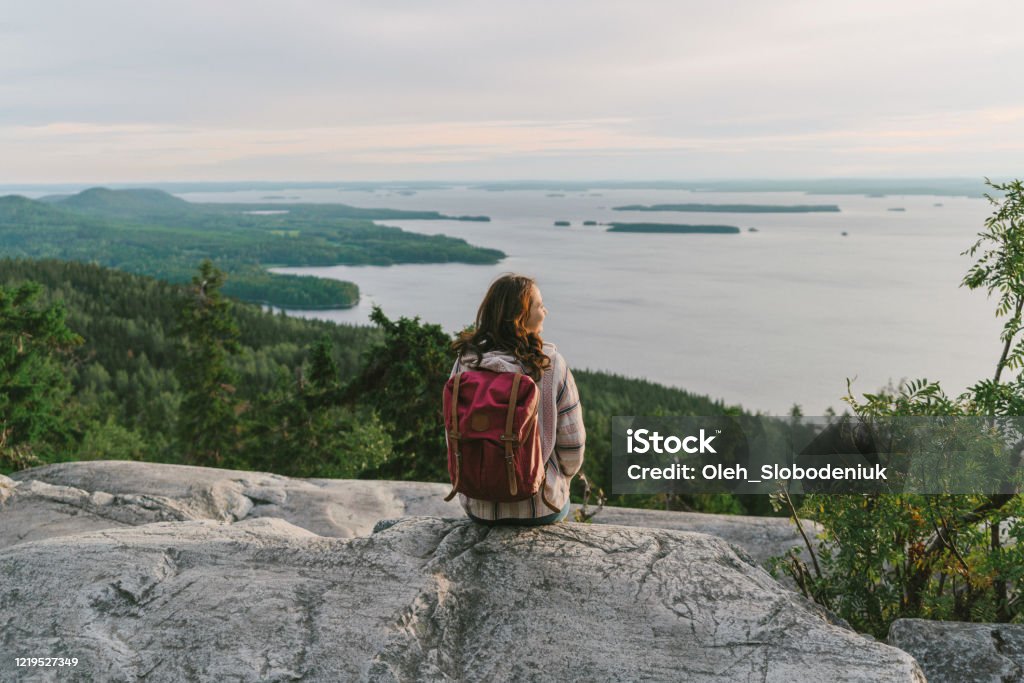 Scenic  view of woman looking at  lake in Finland Scenic view of woman looking at  lake in Finland at sunset Finland Stock Photo