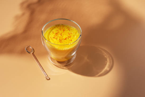 Saffron latte in a glass cup on a beige background, golden milk, hard light,space for text.