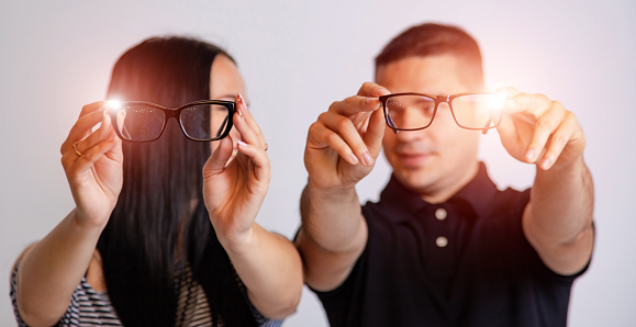 Portrait of a young couple looking through glasses isolated on white. Presenting spectacles
