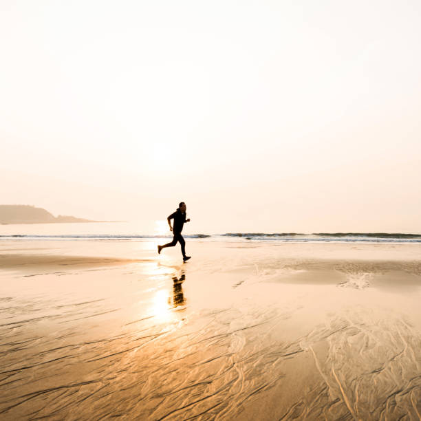 istock Man running on the beach at sunset 1219527501