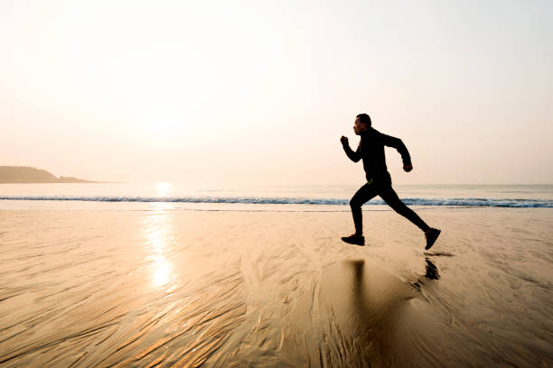 istock Man running on the beach at sunset 1219527582