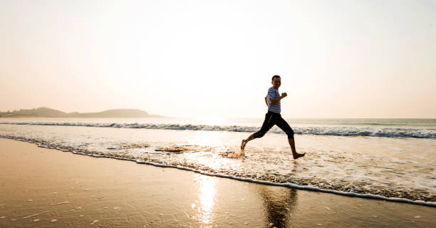 istock Man running on the beach at sunset 1219527886