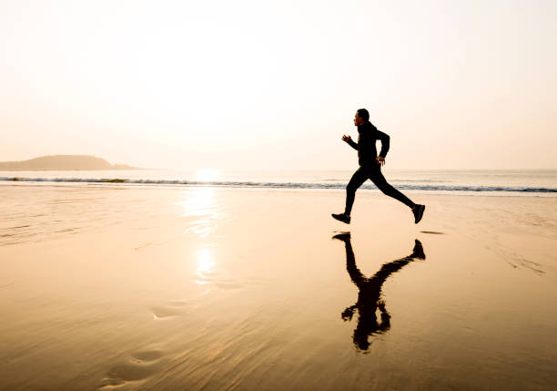 istock Man running on the beach at sunset 1219527910