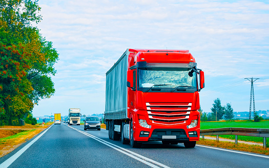 Truck in summer road of Poland. Trucker in highway. Lorry doing logistics work. Semi trailer with driver. Big cargo car drive. Freight delivery. Transport export industry. Container with goods