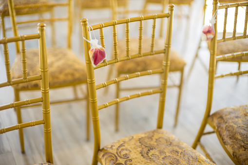 A pack of confetti petals hanging on top of a chair in wedding ceremony
