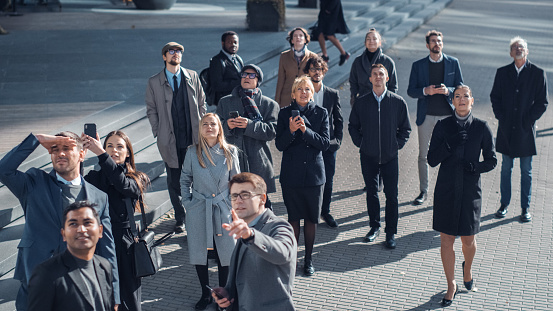 Multicultural Diverse Office Managers and Business People Suddenly Stop on the Street and Look Up. Unbelievable, Fantastic or Tragic Event Happening Live. Crowd Takes Out Smartphones and Record Video.