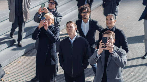 multicultural divers office managers and business people suddenly stop on the street and look up. événement incroyable, fantastique ou tragique qui se passe en direct. crowd sort les smartphones et enregistre la vidéo. - beautiful office people shock photos et images de collection