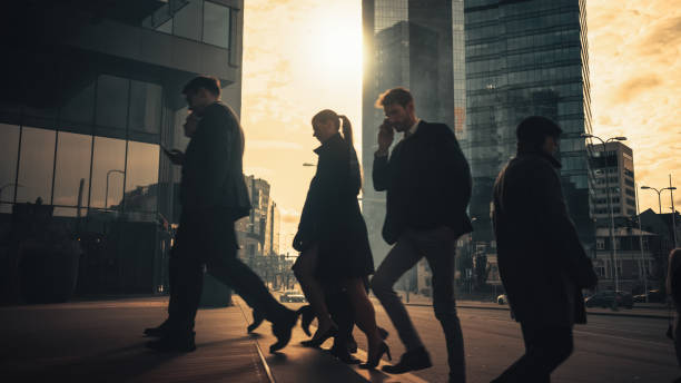 gerentes de oficina y empresarios commute to work on the morning o from office on a sunny day on foot. los peatones están vestidos inteligentemente. personas exitosas con teléfonos inteligentes. día soleado en el centro de la ciudad - smartly fotografías e imágenes de stock