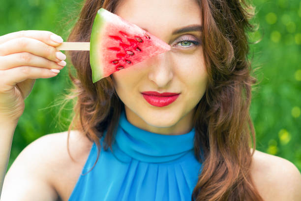 Woman covers eye with watermelon.