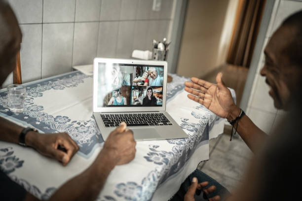 famille sur un appel vidéo utilisant l’ordinateur portatif à la maison - colleague looking at camera indoors lifestyles photos et images de collection