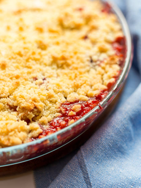 istock Traditional British Red berry crumble in glass baking dish with cloth on white background. Close up. Delicious dessert in rustic style, selective focus 1219537882