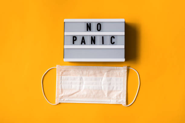 istock Surgical mask with text NO PANIC on white lightbox isolated on yellow background. Stop virus. Coronavirus pandemic. Concept Of Air pollution, flat lay banner 1219538772
