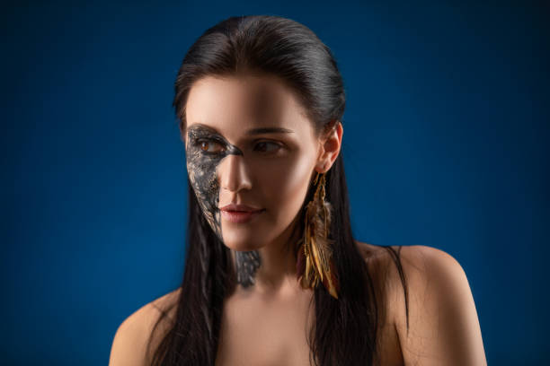 ritratto di giovane donna bruna sensuale con body art di uccelli corvo nero sul viso. - tattoo women bird shoulder foto e immagini stock