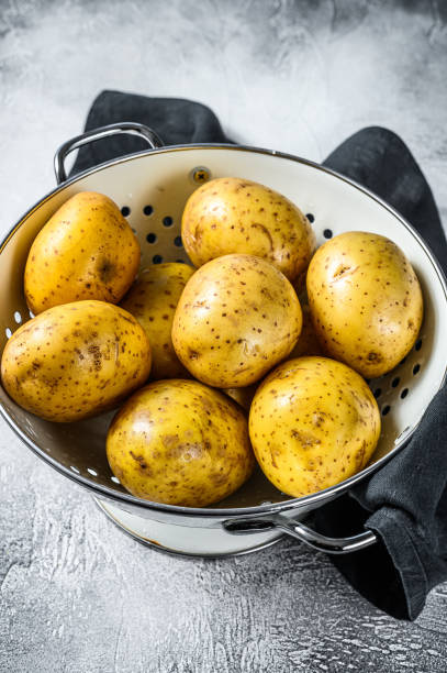 istock Raw washed potatoes in a colander. Gray background. Top view 1219541921