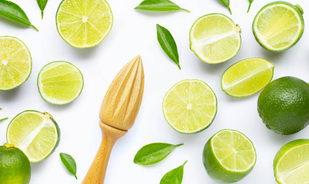 istock Fresh limes and leaves with wooden juicer on white. 1219542036