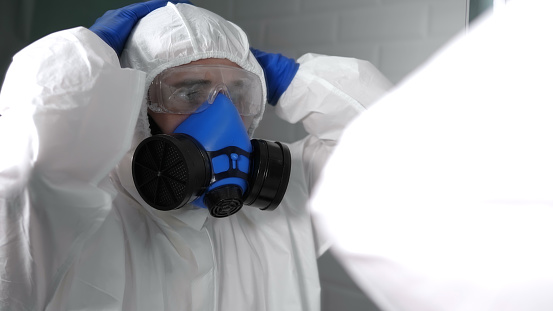 Close up. Scared and shocked doctor or virologist in bio suit and protective mask looking in the mirror. Professional shot in 4K resolution. 054. You can use it e.g. in your commercial video, medical, business, presentation, broadcast