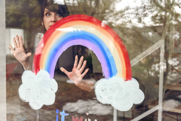 istock Woman painting a rainbow on a window 1219545868