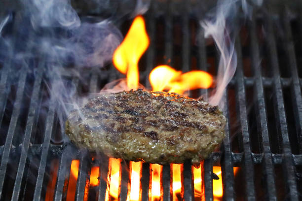 istock Burger barbeque being cooked on hot grill with smokey fire. 1219547716