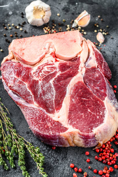 istock Raw beef shank with spices and herbs. Black background. Top view 1219548507