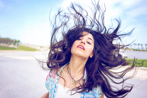 Close up portrait of a beautiful woman outdoors. Waving her hair.