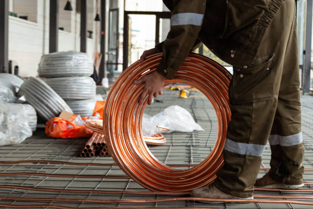 istock Plumber laying copper pipes on floor with warm heating 1219549585