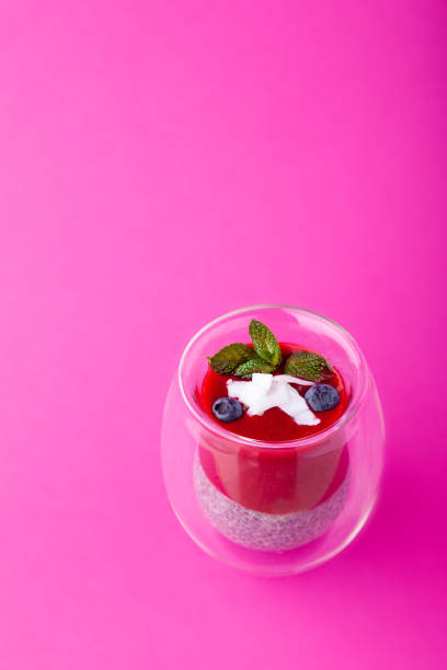 istock Chia pudding with berry puree in glass on pink background 1219549749