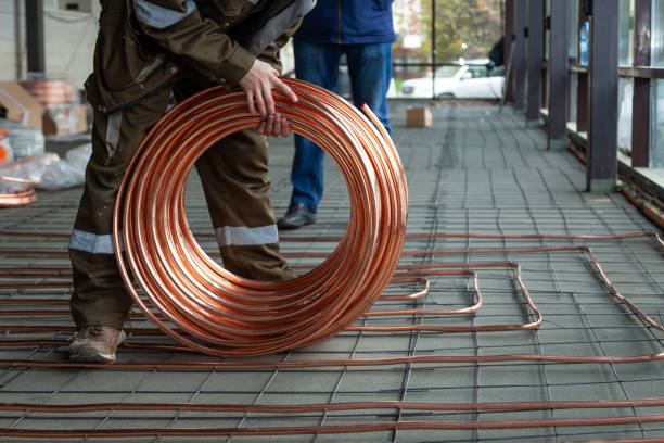 istock Plumber laying copper pipes on floor with warm heating 1219549862