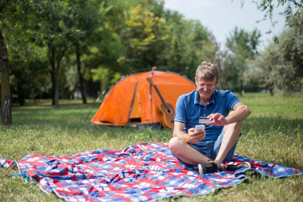 istock Cheerful senior man shopping online while having picnic 1219550088